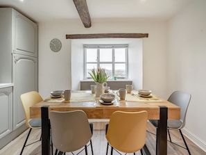 A dining area with a wooden table, four chairs, and a window with a view.