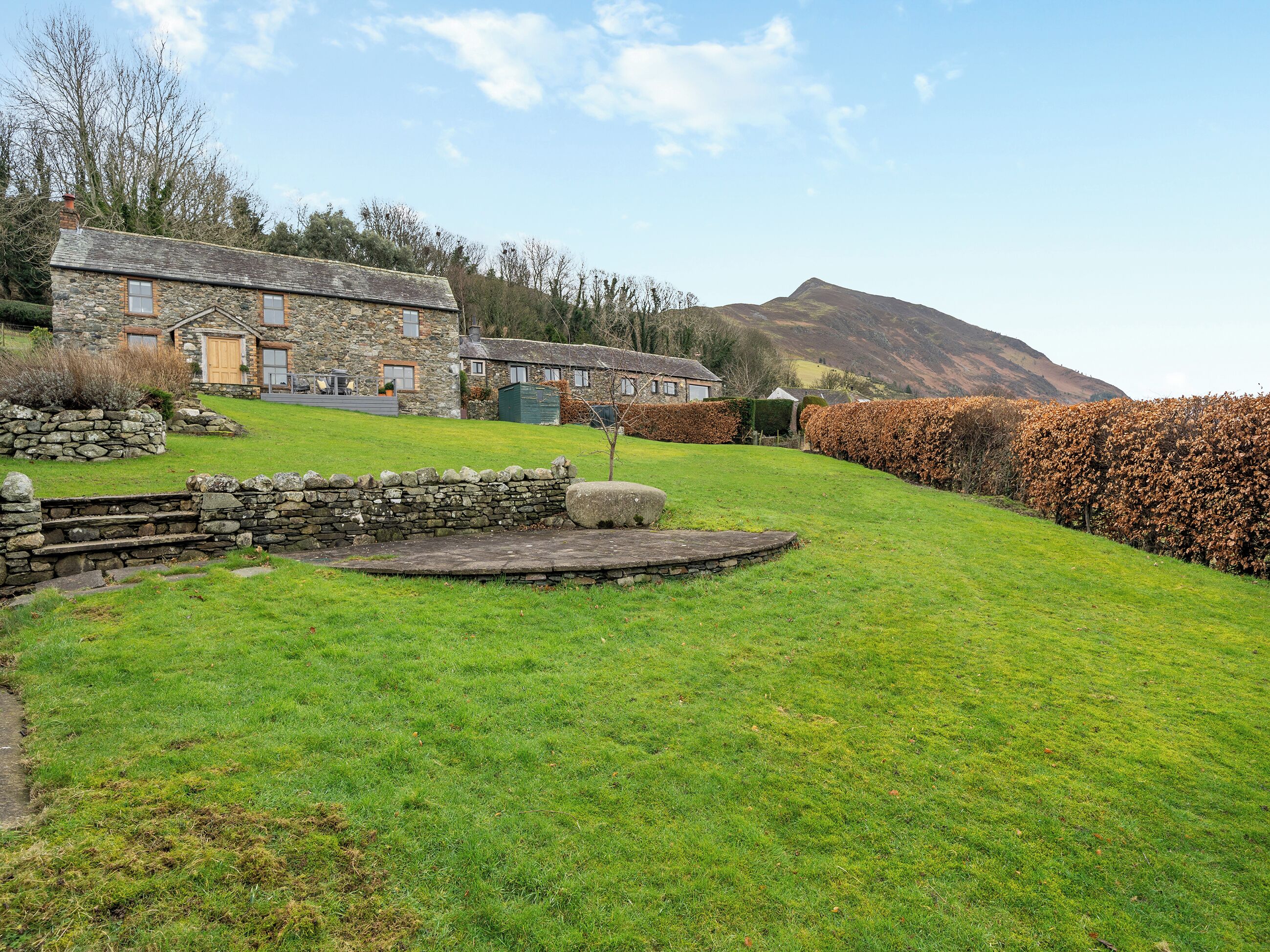 A stone house with a stone staircase leading to a wooden deck.