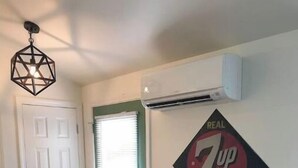 Una habitación con una mesa de comedor de madera, una silla, una puerta verde y un cartel en la pared que dice 'REAL 7UP LIKES YOU'.