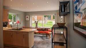 Una cocina moderna con armarios de madera, un comedor con banco y vistas al jardín.