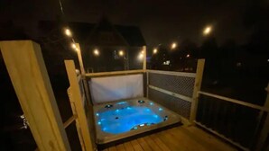 Ein Whirlpool auf einer Holzterrasse bei Nacht.