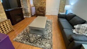 Ein Wohnzimmer mit einer Couch, einem Couchtisch, einem Fernseher und einem Kamin.