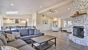 A spacious living area with a gray sectional sofa, a coffee table, and a stone fireplace. - Fully Remodeled Hillsboro Home w/ Home Theater! (Hillsboro)