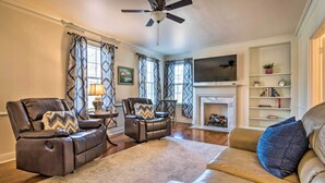 A living room with a fireplace, leather sofas, and a ceiling fan. - Little Rock Home ~ 5 Mi to Downtown! (Little Rock)