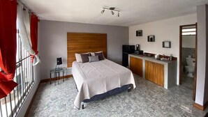 Een slaapkamer met een bed, nachtkastje, bureau, stoel, kast, spiegel en een badkamer.