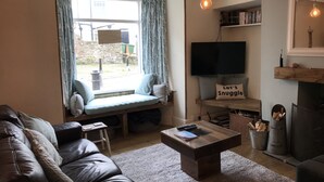 Un salon chaleureux avec un canapé en cuir, une table basse, un téléviseur et une cheminée.