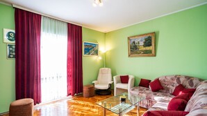 Un salon avec un canapé, des fauteuils, une table basse en verre et un rideau rouge.