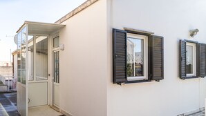 Un bâtiment à la façade blanche, doté d’une porte en verre et de deux fenêtres avec des volets.