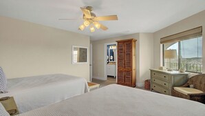 A bedroom with two beds, a ceiling fan, a dresser, a chair, and a window with a view. - 417 Seascape by Avantstay Beachfront Condo w/ Communal Pool Access (Isle of Palms)
