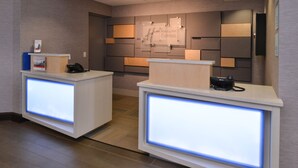 A reception desk with illuminated panels, a wall-mounted sign, and a phone. - Holiday Inn Express Olean (Olean)