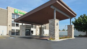 A hotel with a covered entrance, stone pillars, and a clear blue sky. - Holiday Inn Express Olean (Olean)