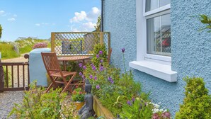 A blue house with a garden, a wooden bench, and a statue. - Picked for its character, charm and gorgeous sea views from every window. (Berea, near St Davids)