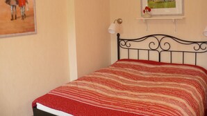 Una camera da letto con un letto, uno scaffale a parete con un quadro incorniciato e una lampada a parete.