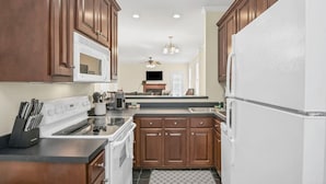 A modern kitchen with wooden cabinets, a white refrigerator, a stove, and a microwave.