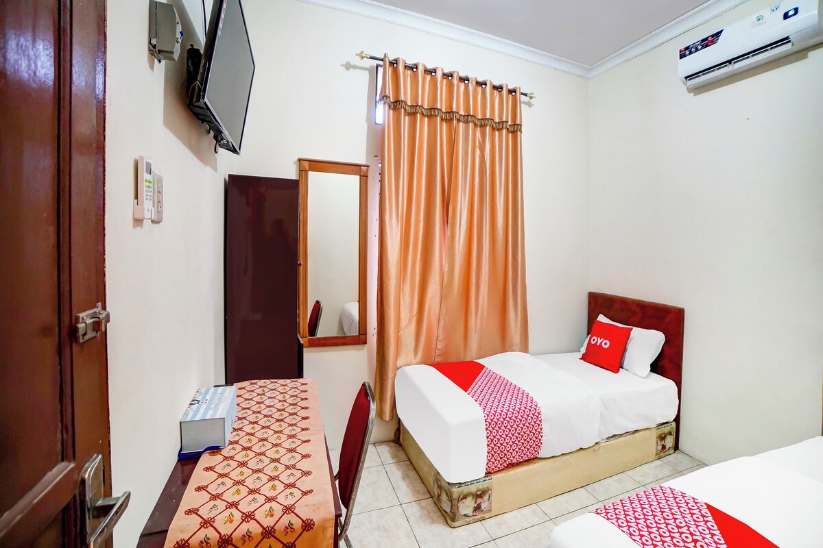 Una habitación de hotel con cama, escritorio, espejo y equipo de aire acondicionado.
