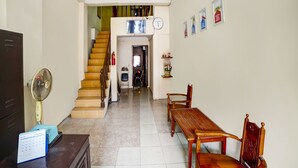 A spacious living area with a wooden staircase, a dining table with chairs, a television, and a calendar on a desk. - OYO 91199 Felicia Homestay (Medan)