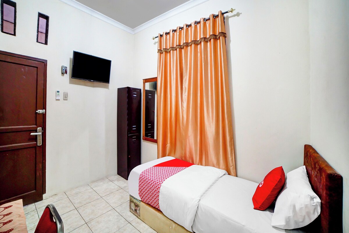 Un dormitorio con cama, televisor, armario y puerta.
