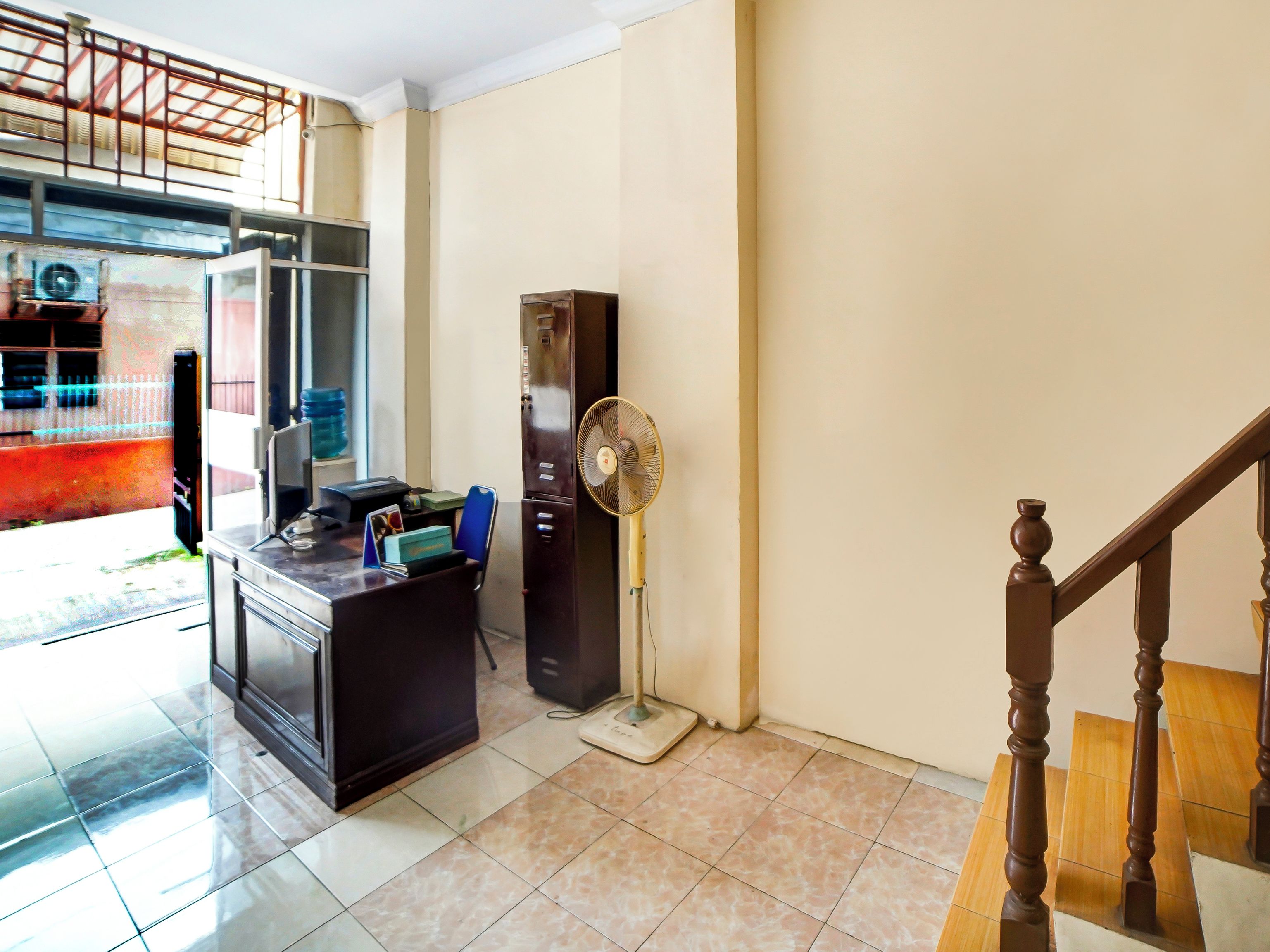 A hotel room with a kitchenette, a standing fan, and a staircase.
