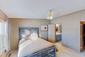 Relax in this serene bedroom with a large bed, ceiling fan, and framed artwork.