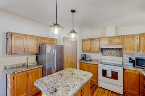 Enjoy cooking and entertaining in this well-equipped kitchen with a central island, wood-paneled cabinets, and modern appliances.