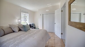 Quarto com cama, janela, porta e espelho.