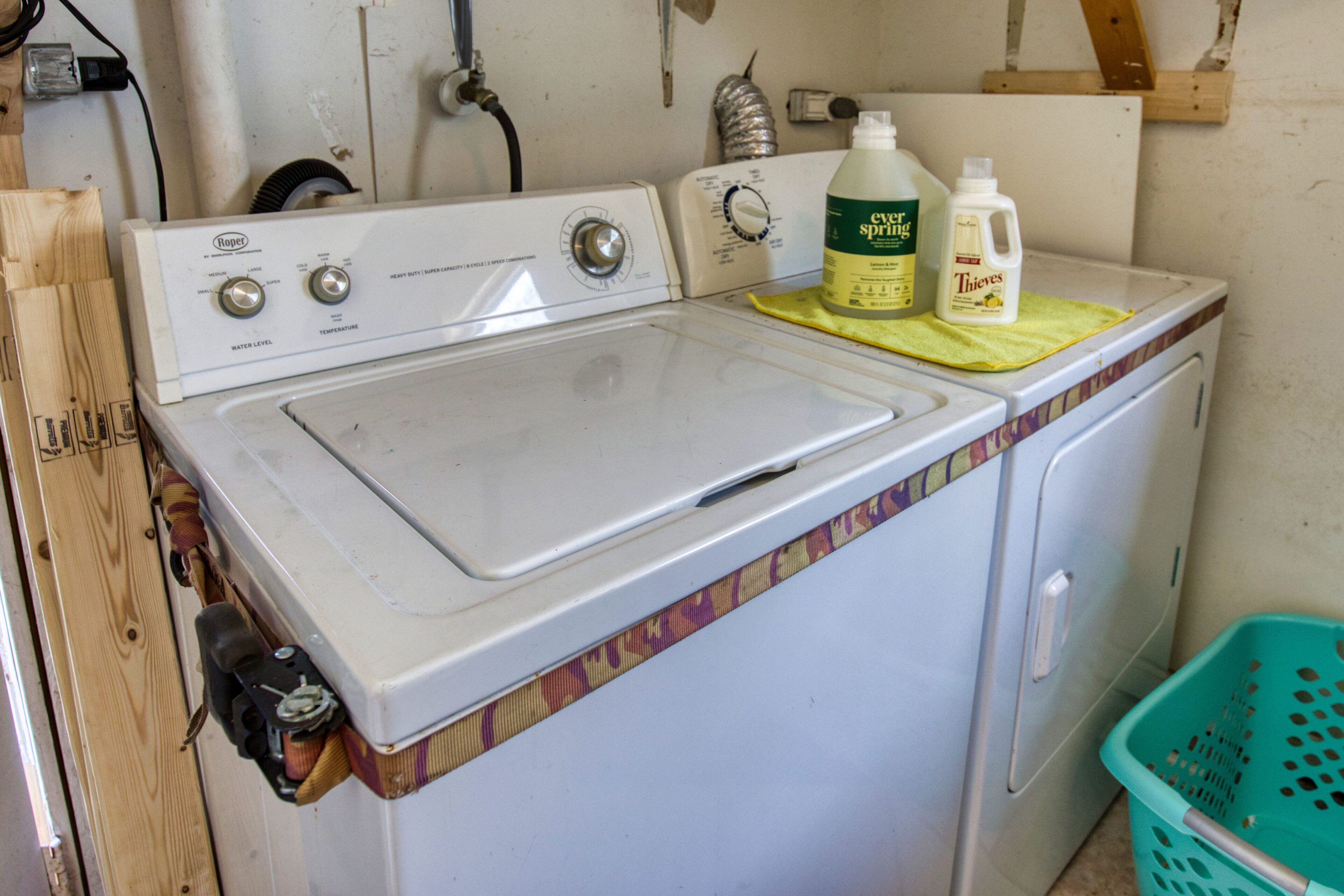 Un lave-linge à chargement frontal doté d’un panneau de commande, d’une bouteille verte de lessive liquide et d’un panier à linge vert.