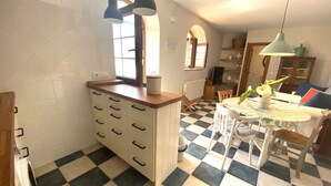 A kitchen with a checkered floor, a white cabinet with multiple drawers, and a dining area with a table and chairs.