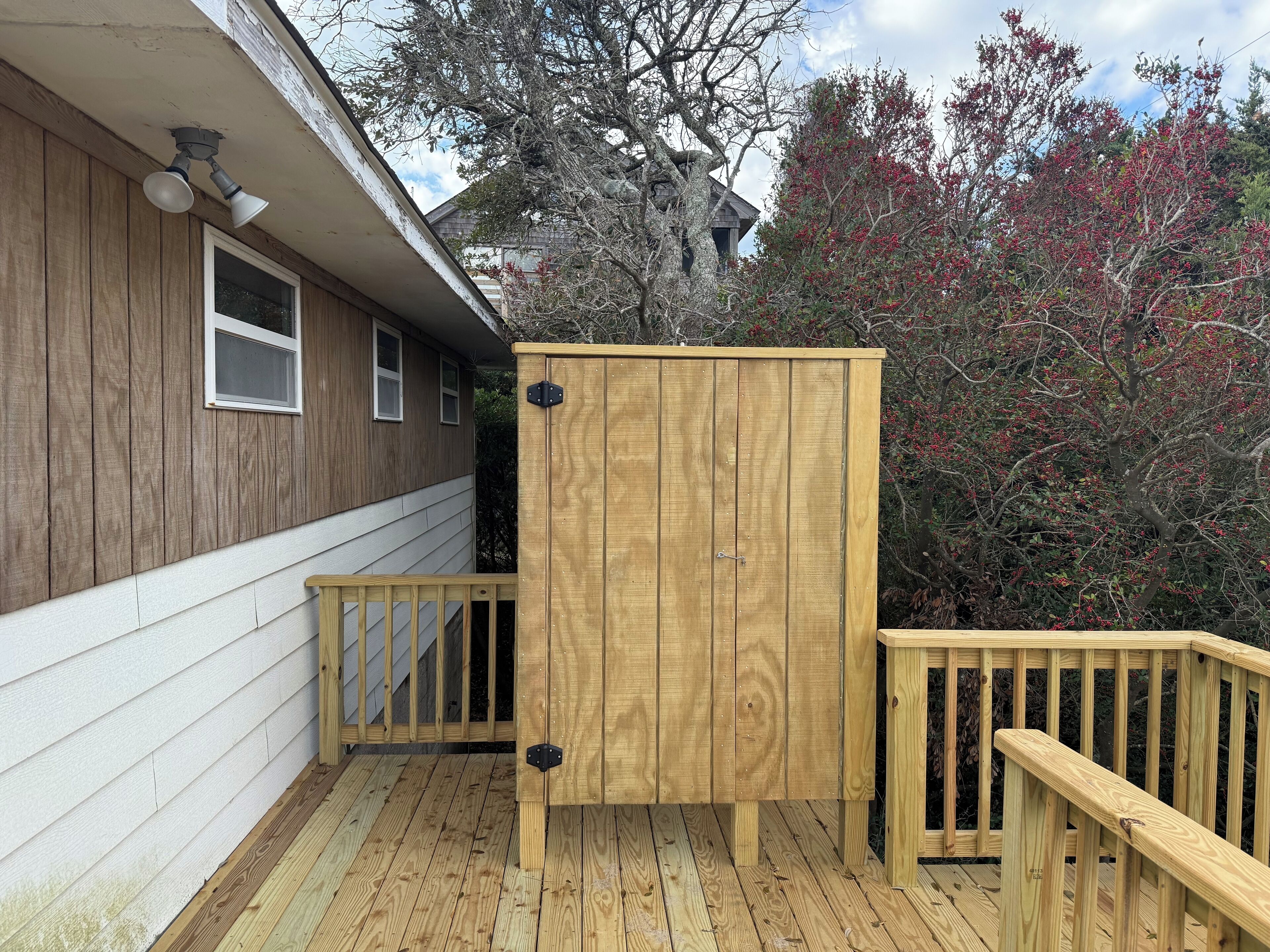 A wooden deck with a wooden privacy screen and a railing.