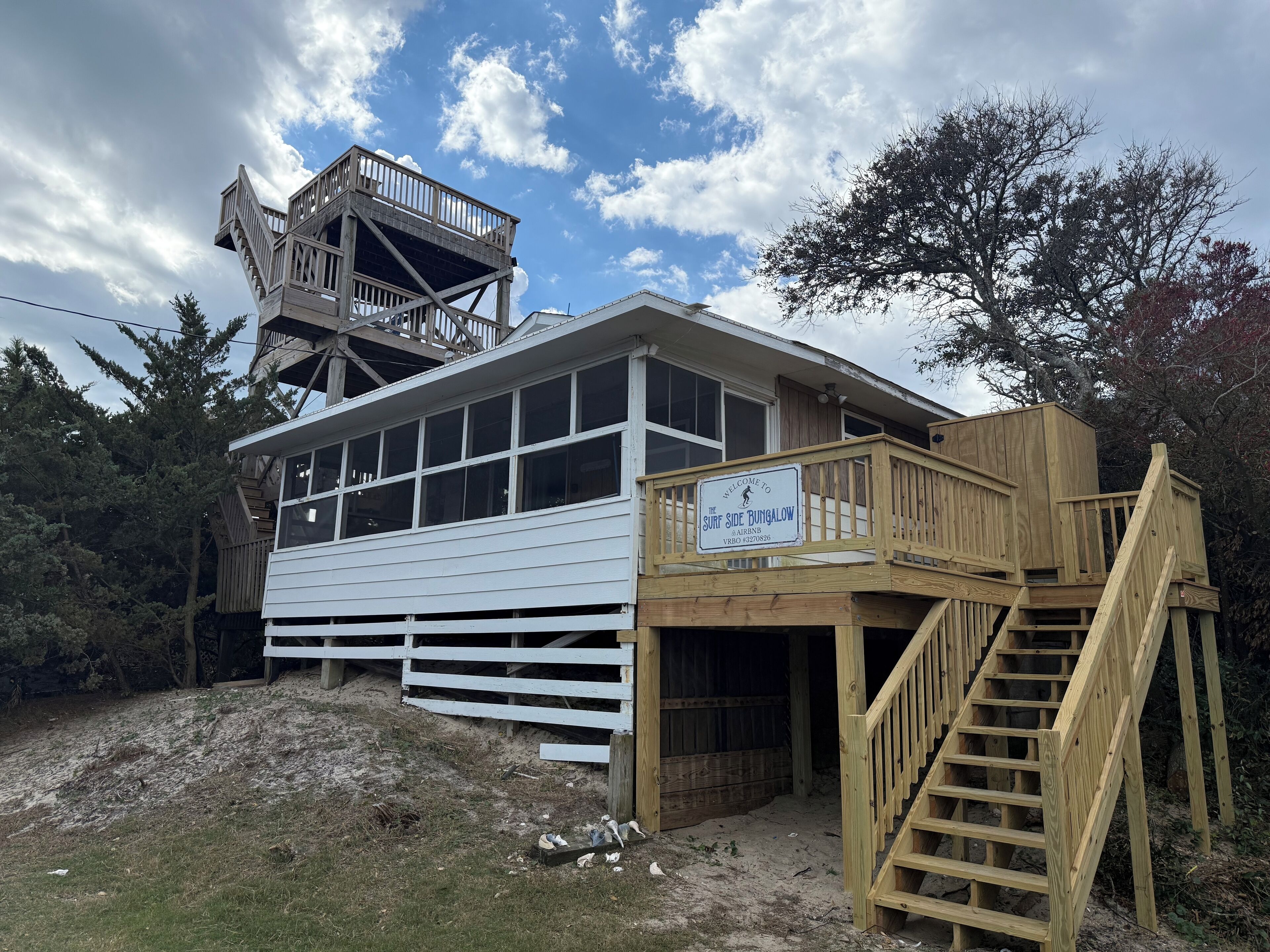 A wooden building with a sign reading "Welcome to the Surf Side Bungalow Airbnb."