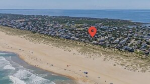 A coastal residential area with a beach, houses, and a red location marker.