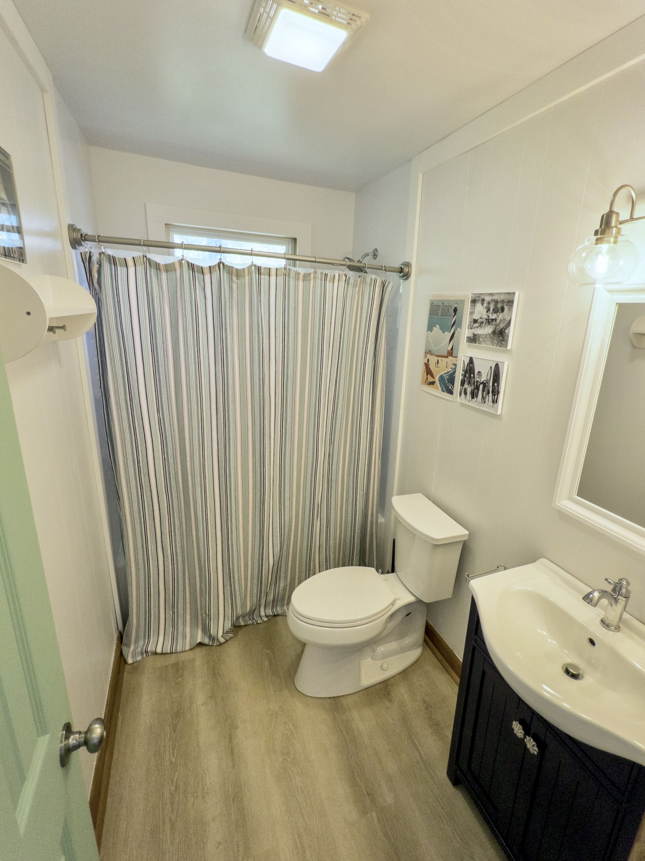 A bathroom with a toilet, sink, and shower curtain.