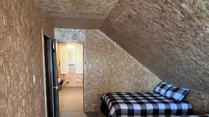 A bedroom with two beds, a wooden wall, and a small bathroom. - Lake front Rustic Cabin in the UP, Snowmobile-ATV trails, Falls, Mackinaw Island (Trout Lake)