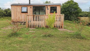 Une cabane en bois avec une terrasse, une cheminée et une fenêtre.