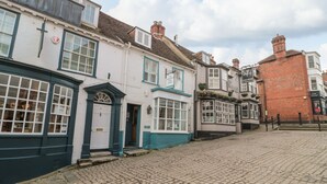 Eine Kopfsteinpflasterstraße gesäumt von traditionellen Gebäuden, darunter ein Pub mit einem Schild, auf dem 'LYMINGTON' steht.