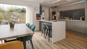 Eine moderne Küche mit einer zentralen Kochinsel, Barhocker und einem Essbereich mit einem Holztisch und Stühlen.