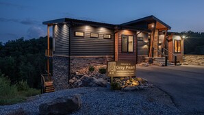 A modern lodge with a stone facade, wooden accents, and a sign indicating it is the Grey Pearl. - Luxury Family and Friends Getaway, Indoor Pool, Theater, Epic Smoky Mtn Views (Sevierville)