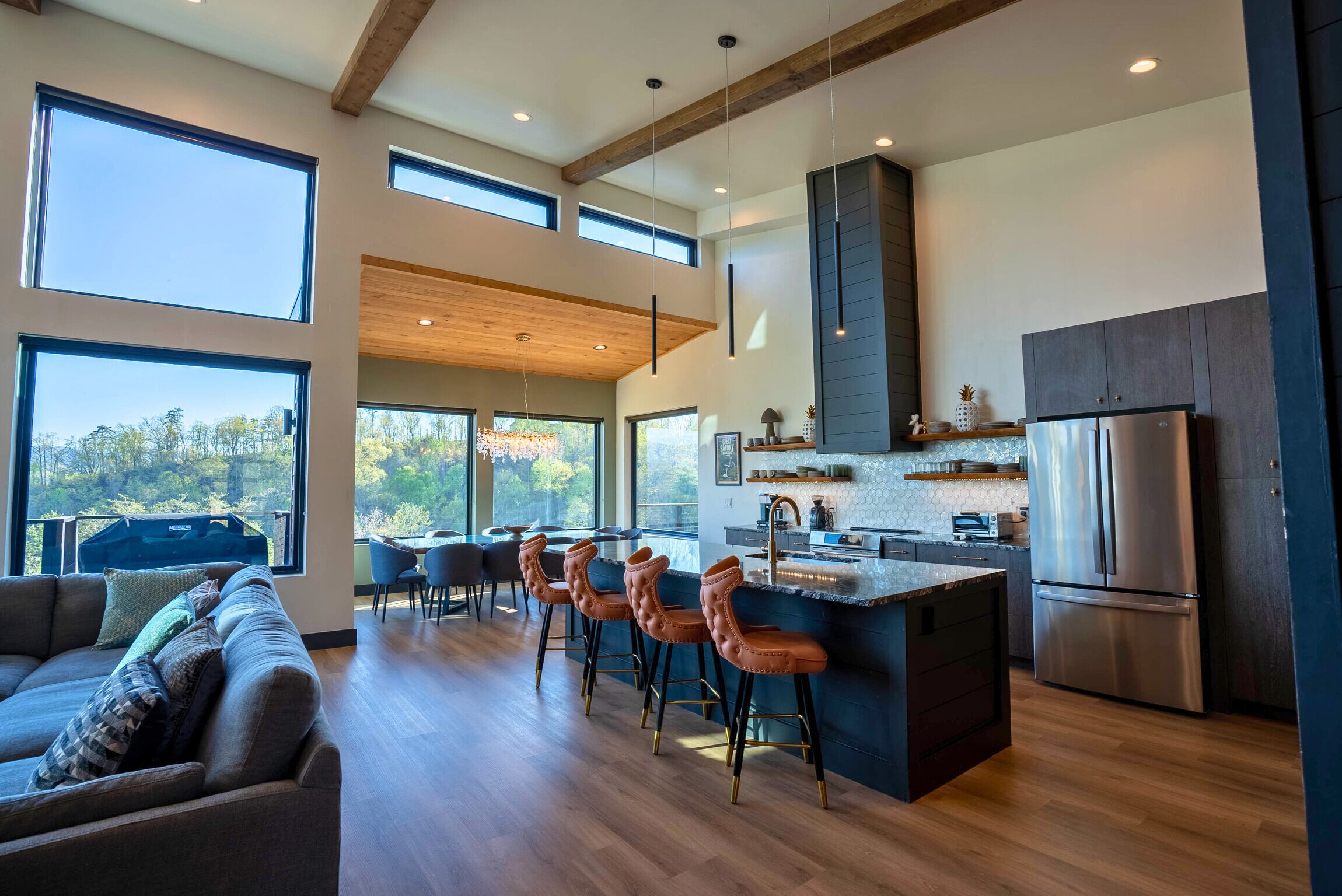 A modern kitchen with a large island, bar stools, and a built-in refrigerator.