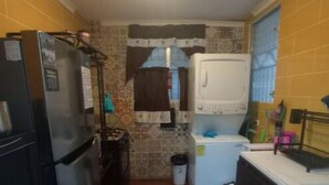 Une cuisine compacte équipée d’un réfrigérateur, d’un lave-linge et d’un évier.