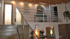 Una escalera con barandas de vidrio, una lámpara colgante y un adorno de pared.