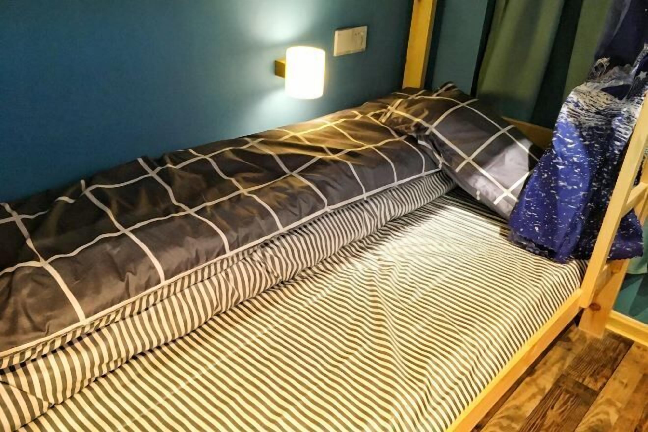 A bunk bed with a striped mattress and a patterned pillow.