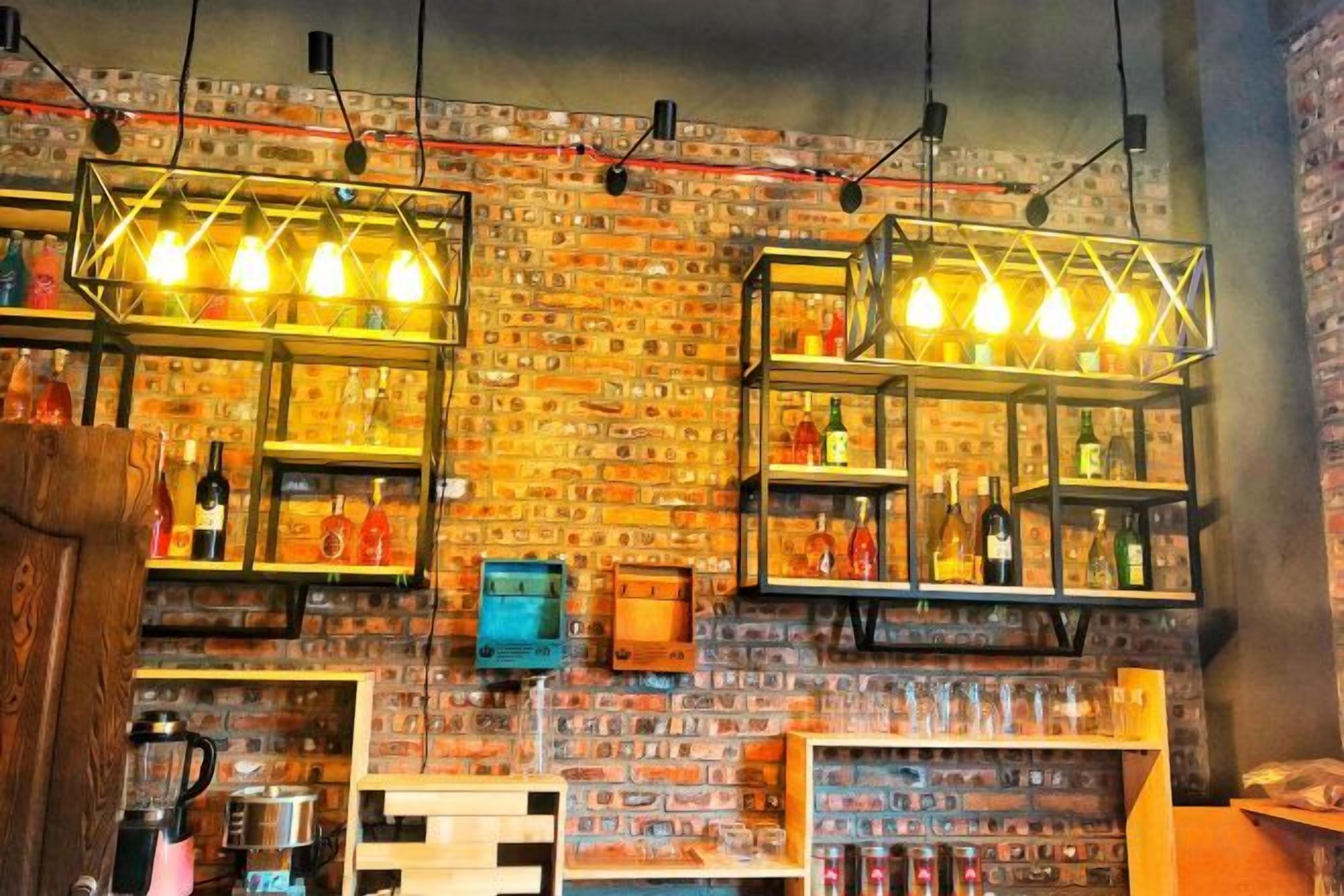 A bar area with shelves of bottles and a brick wall backdrop.