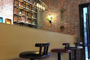 A bar area with stools, a brick wall, shelves with bottles, and a hanging light fixture. - Pian an Yi Yu (Chizhou)