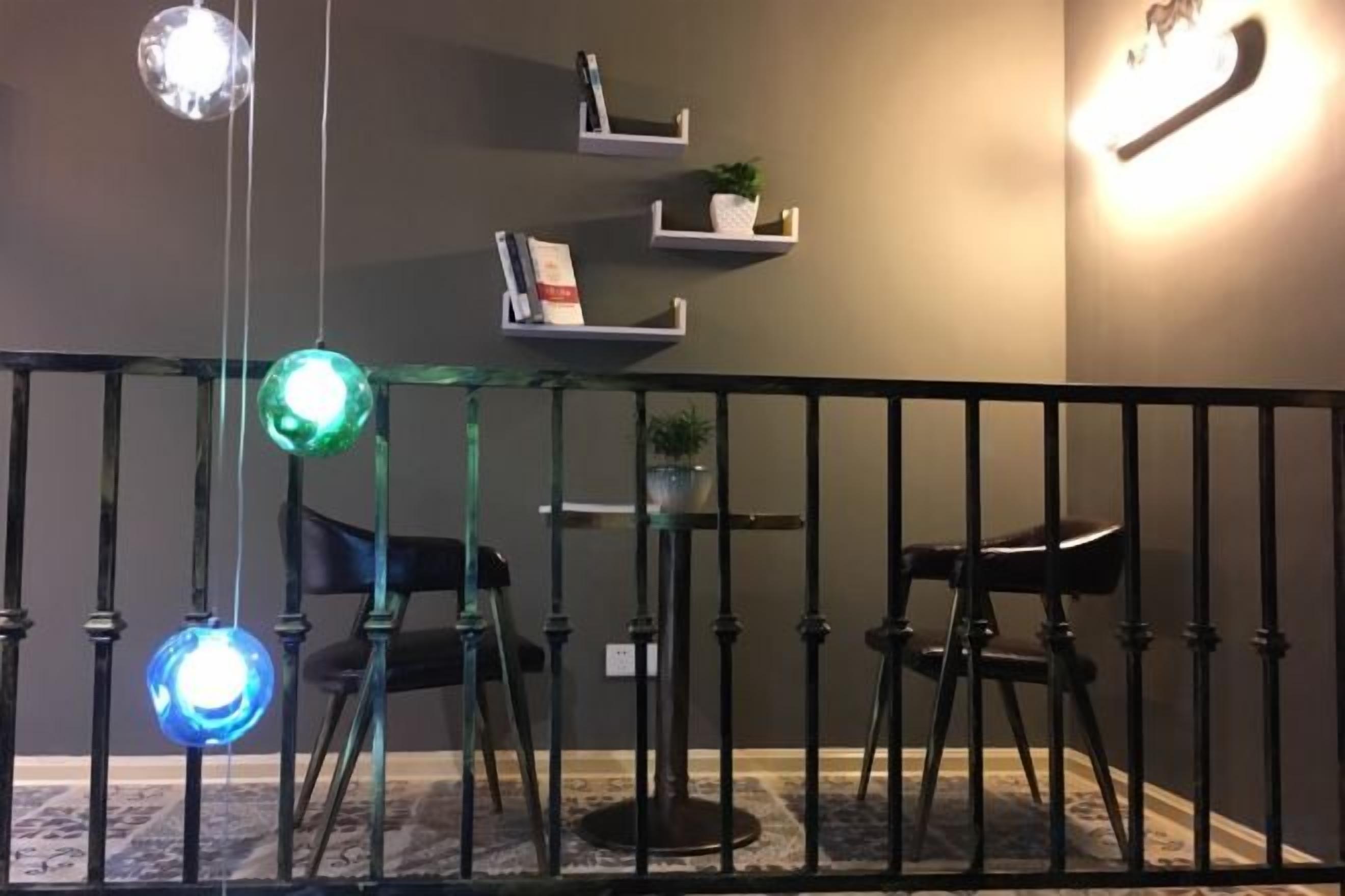 Ein Zimmer mit Glastrennwand, einem schwarzen Stuhl und Regalen mit Büchern und Pflanzen.