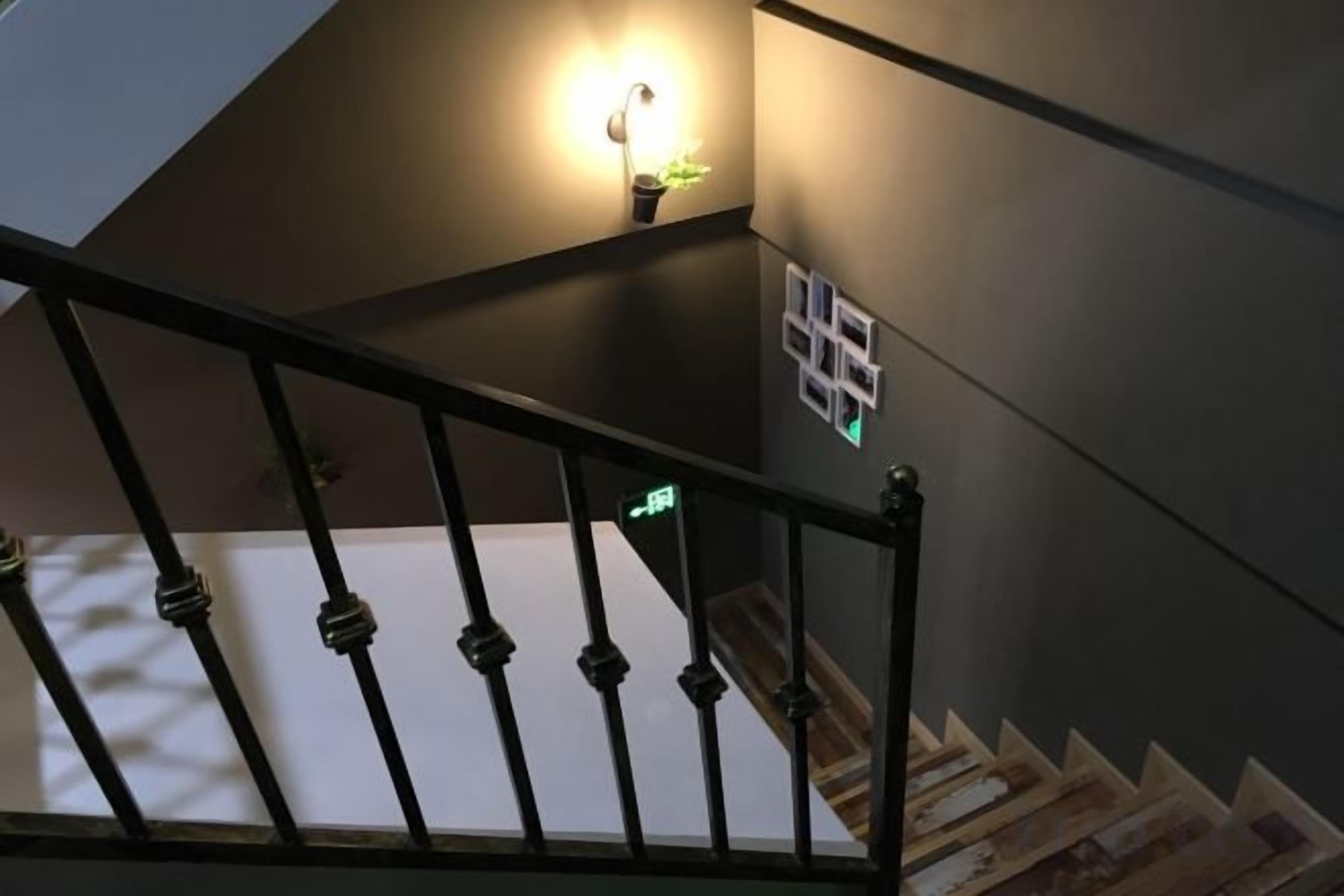 Eine Treppe mit schwarzer Handlauf und einer Wandleuchte.