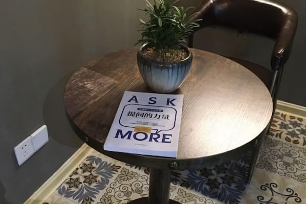 A round table with a potted plant and a sign that reads 'ASK MORE'. - Pian an Yi Yu (Chizhou)