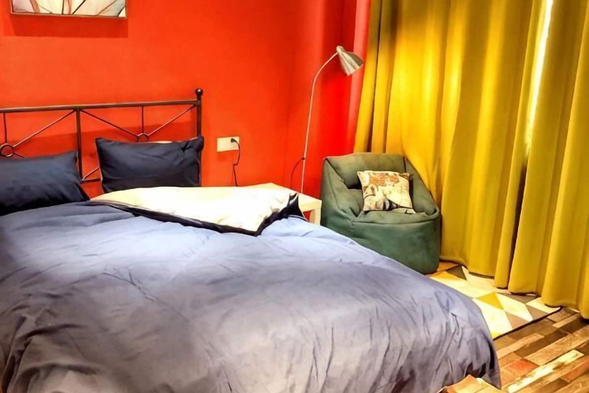 A bed with a metal frame, a green armchair, and a lamp.