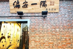 A brick wall with a wooden signboard displaying Chinese characters. - Pian an Yi Yu (Chizhou)