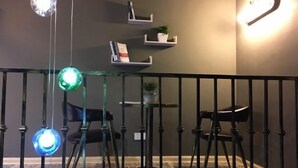 A room with a black metal railing, a glass table with chairs, and shelves with books and a plant. - Pian an Yi Yu (Chizhou)
