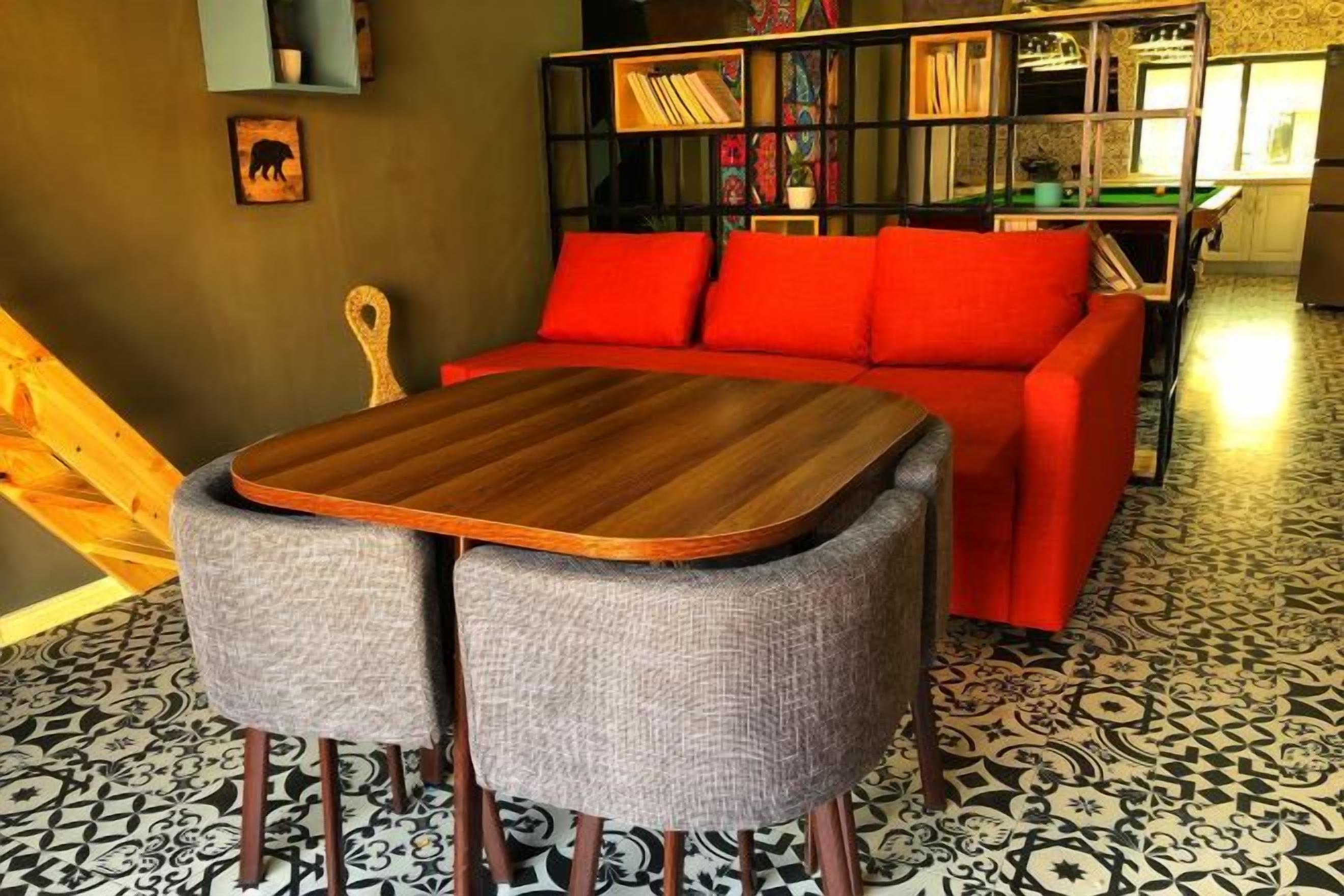 A room with a red sofa, a wooden table, and a patterned floor.