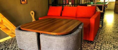 A room with a red sofa, a wooden table, and a patterned floor.